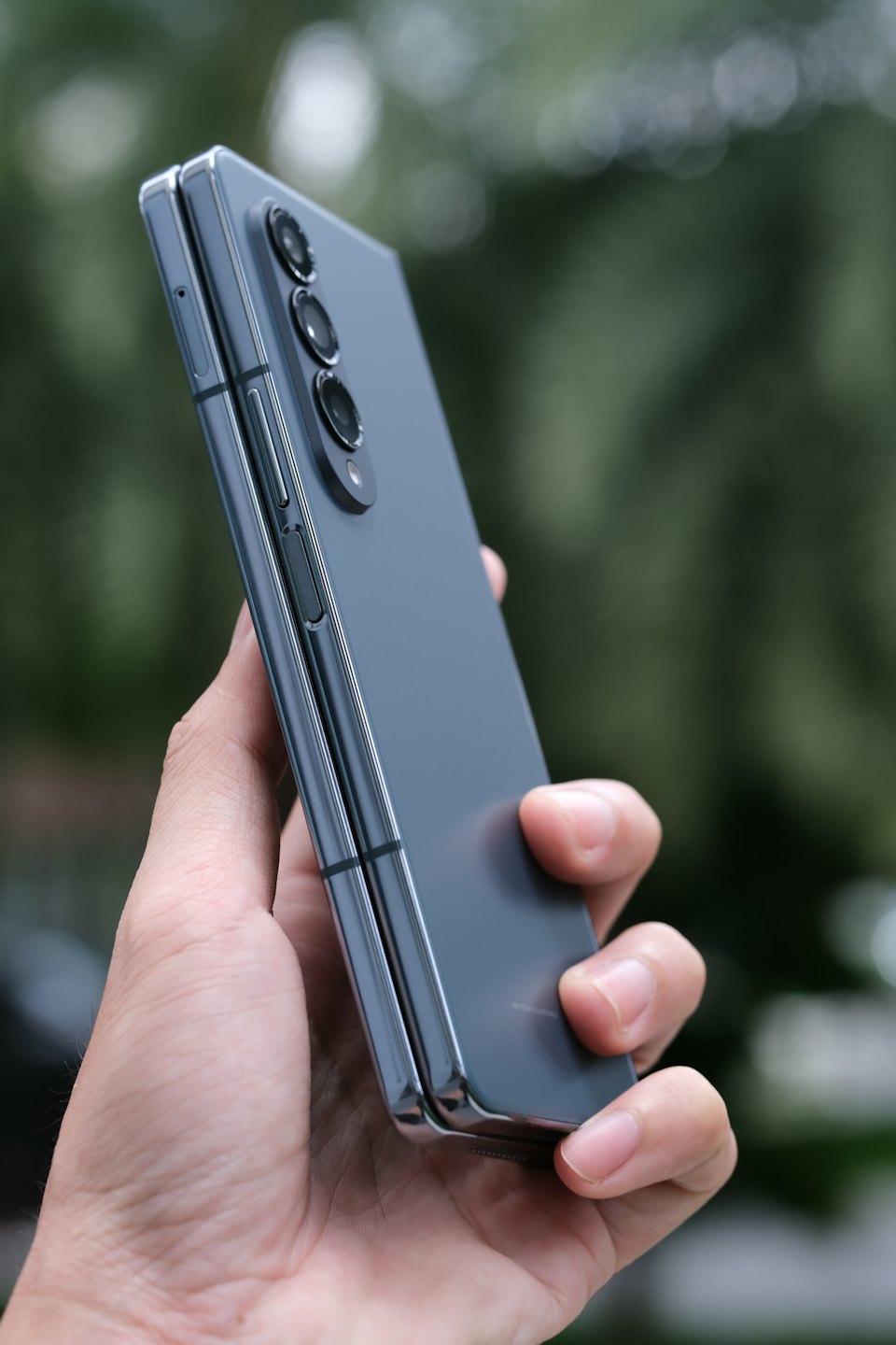 Une main tient un smartphone pliable gris compact.