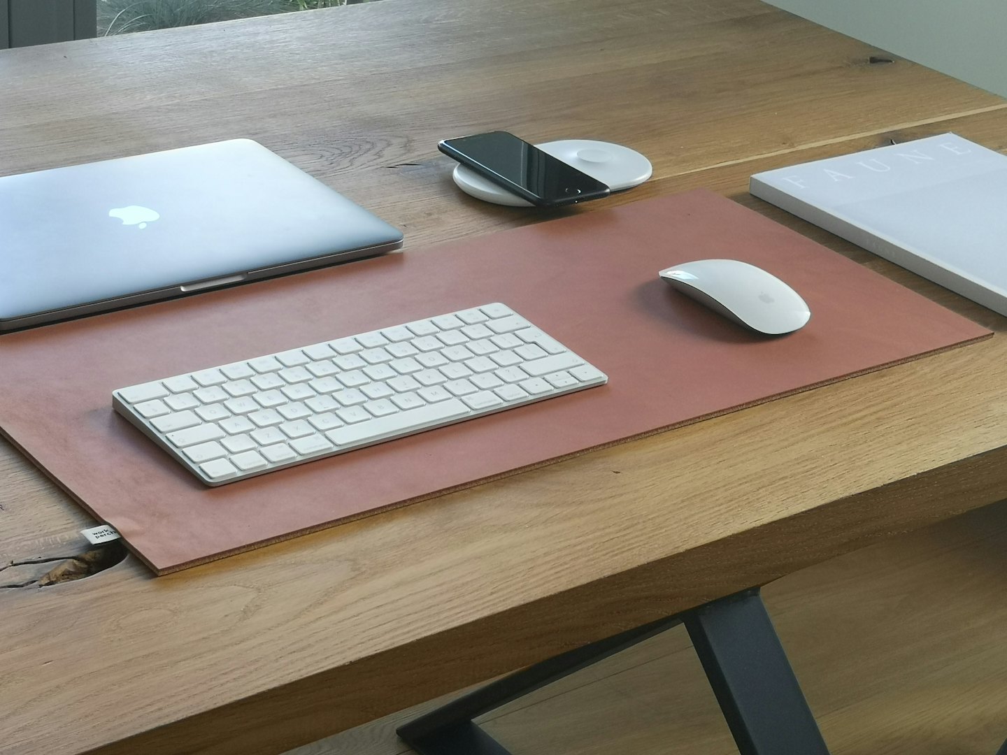 Appareils électroniques et un livre disposés sur un bureau en bois.